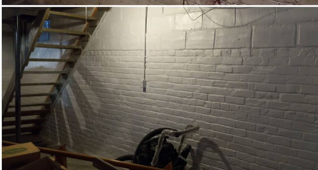 After: the same basement brick wall sealed and finished bright white