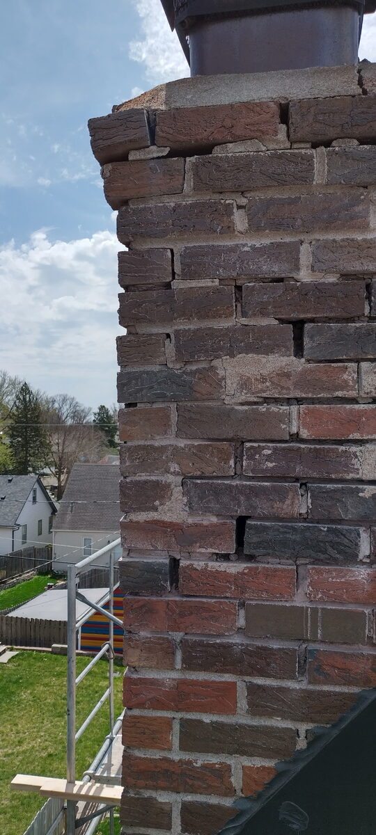 Close-up of open mortar joints and deteriorated brick on an Omaha chimney before rebuild