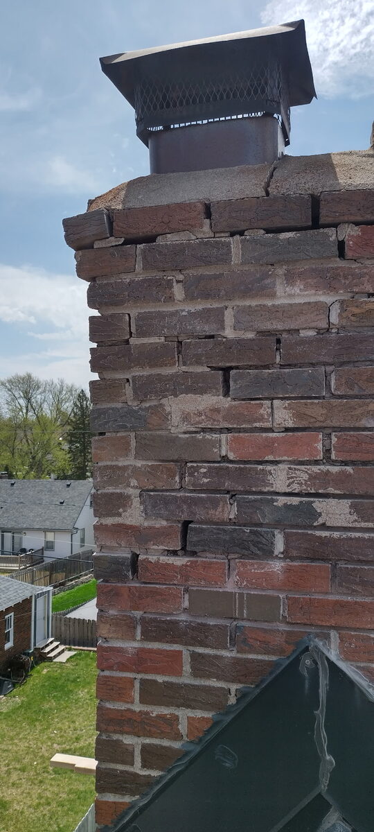 Deteriorated brick chimney with cracked crown and failing mortar joints in Omaha before rebuild