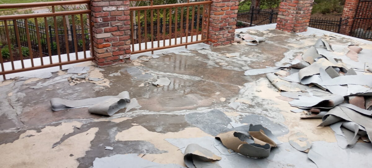 Failed coating being removed from a concrete patio with brick pillars in Omaha