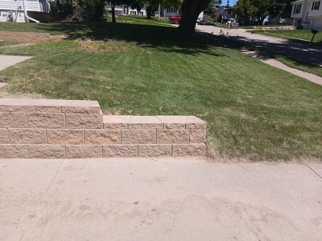 Long block retaining wall running along a sidewalk