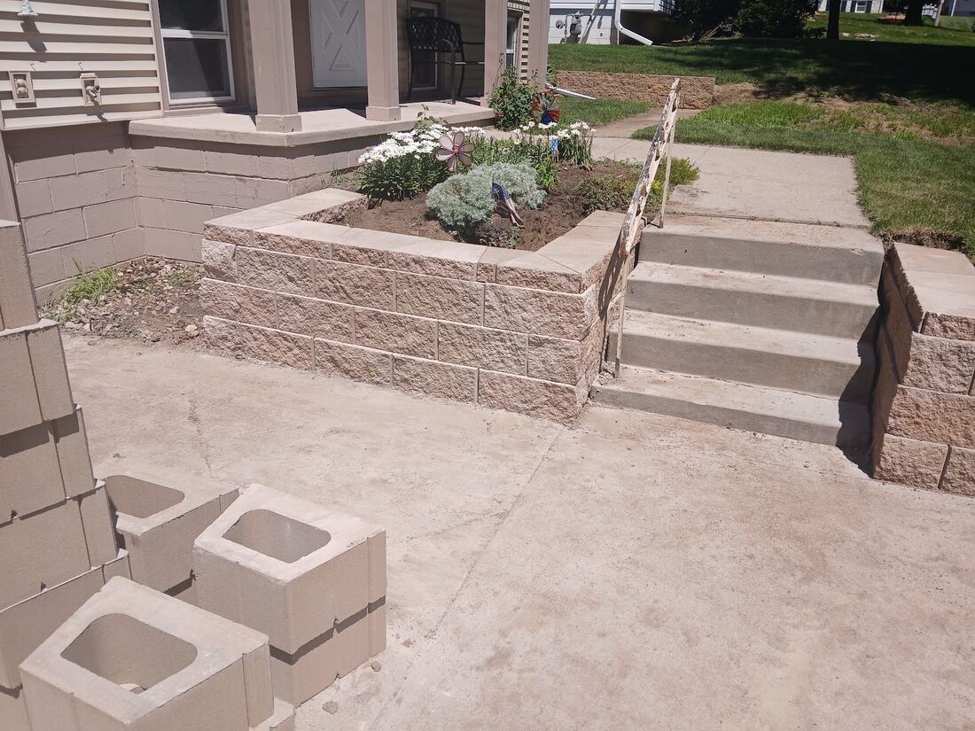Finished planter walls and steps with railing at an Omaha home entry